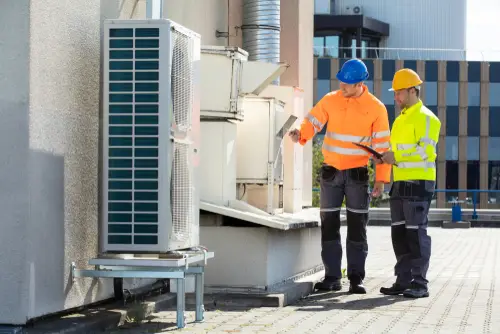 Two men working on a rooftop commercial HVAC system