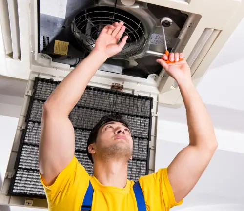 Repair man working on a ventilation system in the ceiling